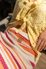 Camisa amarilla de broderie con escote en V, mangas globo y lazos ajustables en el frente.