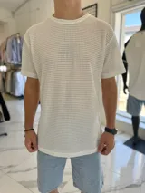 Remera oversize blanca de tejido abierto con textura de red, cuello redondo y mangas cortas.