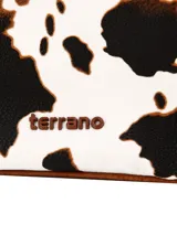 Bolso tipo shopper de la marca Terrano, confeccionado en símil cuero con diseño combinado. Presenta laterales y asas de hombro en color marrón, y panel central con estampado de vaca en blanco y negro. Cuenta con cierre superior y detalles de herrajes metálicos.