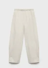 Pantalón de diseño balloon con cintura elástica, tiro medio y pinzas en el bajo. Presenta una textura ligeramente arrugada y forro interior.