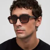 Lentes de sol con montura cuadrada de diseño retro inspirado en los años 70, en color marrón translúcido con cristales polarizados en tono marrón.