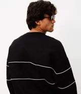 Buzo negro de cuello redondo, manga larga y calce boxy, confeccionado en mezcla de algodón y poliéster. Presenta recortes horizontales con vivos blancos en el pecho y las mangas, además de un diseño bordado con la inscripción "Unlimited Series".