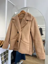 Chaqueta negra con forro tipo corderito, doble botonadura y cuello solapa.