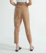 Pantalón cargo de tiro medio color beige, con cintura alta fija, cinturón ajustable para anudar, bolsillos laterales con solapa y botones, recortes verticales en las piernas y cierre frontal con botón y cremallera.