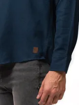 Camisa de franela color azul marino, de manga larga, con cuello abotonado, un bolsillo frontal y cierre de botones.