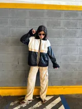 Campera con cuerpo de corderito color beige, mangas y parte inferior de cuero sintético negro con textura tipo cocodrilo. Tiene cuello estilo camisa con solapas de corderito negro, cierre frontal con cremallera y bolsillos laterales.