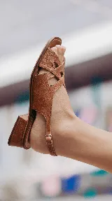 Sandalia de taco cuadrado de 4 cm y punta cuadrada, confeccionada 100% en cuero color tostado. Presenta un diseño de tiras entrelazadas en el empeine y tira ajustable con hebilla en el talón.