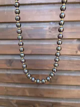 Collar de cuentas de hematite oscuras intercaladas con pequeñas cuentas doradas.