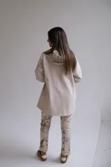 Campera tipo parka de color beige, con cierre frontal completo, capucha con cordones ajustables y mangas tres cuartos con detalle de trabilla y botón.