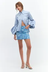 Minifalda de jean celeste con estampado de flores blancas, de corte recto y tiro alto.