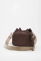 Bolso bandolera de nailon marrón de Bimba y Lola, con cierre de cordón ajustable, bolsillo frontal con cremallera y el logotipo de la marca impreso. Cuenta con una correa ajustable ancha de lona beige y detalles de cuerdas decorativas en los laterales.