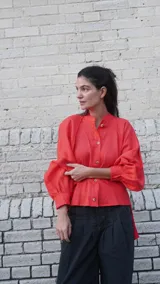 Camisa de lino blanca, de corte oversize, con mangas largas abullonadas, cuello mao y botones. Es más larga en la parte trasera e incluye un tajo en la espalda.