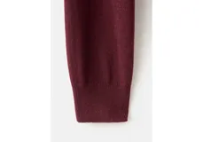 Jersey bordó de punto fino con cuello redondo y manga larga, de corte recto y clásico.