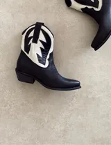 Bota corta estilo western de cuero color marrón, con taco cuadrado de 5 cm y diseño clásico. Presenta un acabado desgastado en la puntera y el talón.