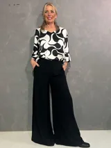 Pantalón de vestir negro, estilo oxford, confeccionado en viscosa y lycra, con pretina frontal, elástico en la parte trasera y bolsillos laterales.