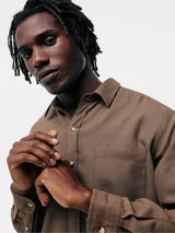 Camisa de manga larga en color gris, con cuello clásico, cierre frontal de botones y un bolsillo en el pecho.