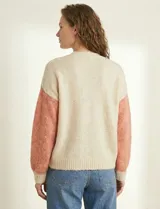 Cardigan de punto con escote en V y abotonadura frontal. Presenta un diseño colorblock con paneles en beige claro, rosa salmón y beige con lentejuelas dispersas. Las mangas son largas y abullonadas con puños y ruedo en punto acanalado beige claro.