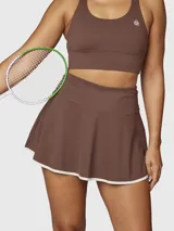Falda deportiva tipo skort color chocolate con borde inferior en contraste blanco. Confeccionada en tejido técnico con short integrado y bolsillo oculto.