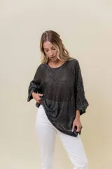 Buzo de tejido liviano con brillo sutil tipo lurex, color beige o dorado claro. Presenta un calce suelto (oversize) con mangas amplias y cuello redondo. El ruedo tiene un detalle de terminación festoneado con pequeños calados.