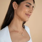 Collar de cadena fina tipo veneciana en oro 18k con dije colgante de diseño estilizado que combina oro y nácar.