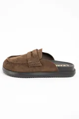 Zueco tipo mocasín destalonado confeccionado en gamuza color marrón, con suela de goma negra y plantilla anatómica.