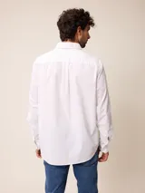 Camisa de manga larga en color blanco, confeccionada en algodón. Presenta cuello abotonado, cierre frontal con botones y un bolsillo en el pecho.