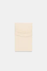 Top de punto color crema, con escote recto y hombros descubiertos, manga larga y diseño ajustado.