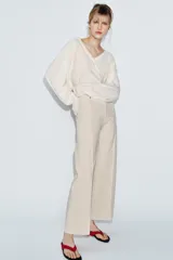 Jeans de tiro alto confeccionados en mezcla de algodón, con diseño de pierna ancha y costura marcada en el delantero. Presenta cintura con trabillas, cierre frontal con cremallera, botón y gancho metálico, y bolsillos de plastrón en la espalda.