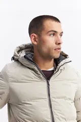 Campera puffer con capucha, diseño acolchado, cierre frontal y bolsillos laterales. Presenta un interior en contraste de color verde oliva.