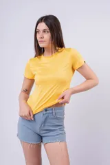 Remera ajustada de manga corta, color amarillo vibrante, con cuello redondo. Presenta un pequeño detalle de etiqueta negra en la manga derecha.