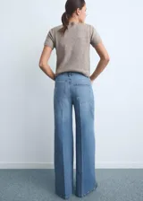Pantalón jeans de tiro alto y corte wide leg, confeccionado en tejido de algodón con elasticidad. Presenta diseño de cinco bolsillos, cierre frontal con botón y cremallera, y trabillas para cinturón.