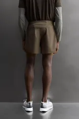 Short de running 2 en 1 color beige, confeccionado en tejido técnico ligero y elástico con malla interior integrada. Presenta cintura elástica ajustable con cordón, bolsillo trasero con cierre y aberturas laterales en el bajo.