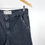 Bermuda de jean negro con detalle de rotura en el bolsillo y costuras a la vista.