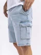 Bermuda de jean azul oscuro, estilo cargo, con bolsillos laterales con tapa a la altura del muslo.