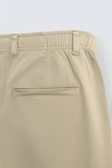Pantalón de corte recto confeccionado en tejido de sarga con estructura diagonal. Presenta cintura elástica, bolsillos delanteros, bolsillos traseros de vivo y cierre frontal con cremallera y botón.