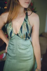 Vestido largo con estampado tie-dye en tonos violeta y fucsia, escote en V con detalles bordados dorados, cut-outs laterales bajo el busto y tirantes finos que se cruzan y atan en la espalda.