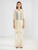 Camisa larga negra de punto calado con cuello camisero, manga tres cuartos y cierre frontal con botones.