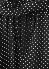 Blusa de poliéster color negro con estampado de lunares blancos, cuello alto con detalle de lazo, manga larga con puños elásticos y diseño recto.