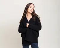 Sacón negro de lana merino, con mangas largas y bolsillos frontales.