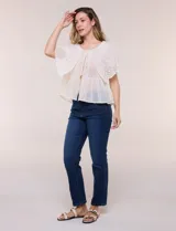 Blusa de estilo romántico color beige confeccionada en algodón, con escote amplio, importante volante capa en broderie calado, cartera frontal con botones tipo perla, bordados verticales calados, cintura marcada con bajo peplum y ruedo recto festonado.