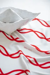 Pañuelo de seda blanco con estampado de líneas curvas en color verde lima, y texto sutil en la tela.