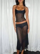 Conjunto de dos piezas color negro confeccionado en tul plumeti transparente con lunares. Incluye un top de escote recto con breteles finos y una falda midi de tiro bajo.