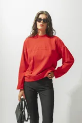 Buzo de tejido de punto color rojo, con cuello alto y manga larga, corte holgado y bordado frontal con la palabra "ROTUNDA".