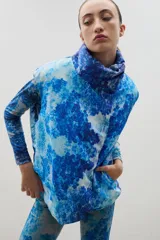 Chaleco puffer con cuello alto y cierre frontal oculto, con estampado forestal en tonos azules.