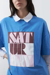 Remera de manga corta con corte boxy fit, color blanco, con estampa frontal geométrica en tonos azul, rosado y marrón.