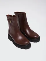 Bota de caña media color marrón, confeccionada en cuero, con suela track negra y detalle de hebilla lateral.