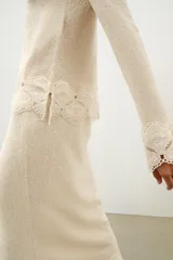 Top de tejido rústico color beige con cuello redondo y mangas largas, con aplicación de crochet a tono en los puños y el ruedo.