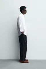 Camisa de corte regular fit confeccionada en tejido de algodón con diseño de rayas verticales. Presenta cuello abotonado, manga larga con puños abotonados, bolsillo plastrón en el pecho y cierre frontal con botones.