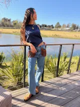 Jeans tiro medio de corte recto y calce holgado, color azul claro. Cuenta con bolsillos delanteros decorados con flecos de gamuza marrón.