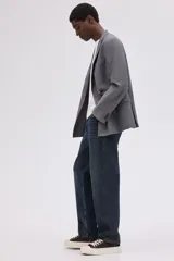 Jean de cinco bolsillos en denim de algodón grueso, color azul oscuro con efecto lavado. Modelo de corte holgado de cadera a bajo con pierna redondeada ancha y tiro bajo. Cintura estándar con cierre de botón y cremallera.